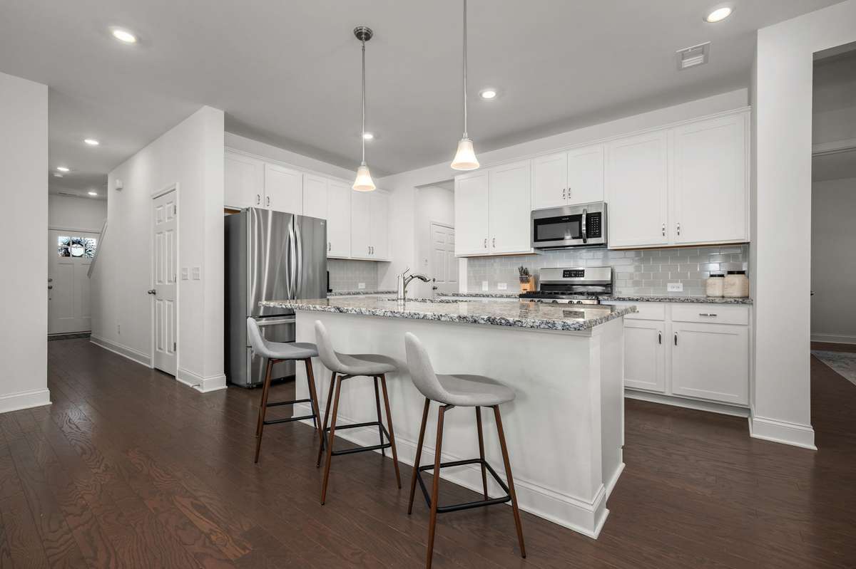 Open kitchen featuring white cabinets, granite counters, tile backsplash, stainless appliances, and large pantry!