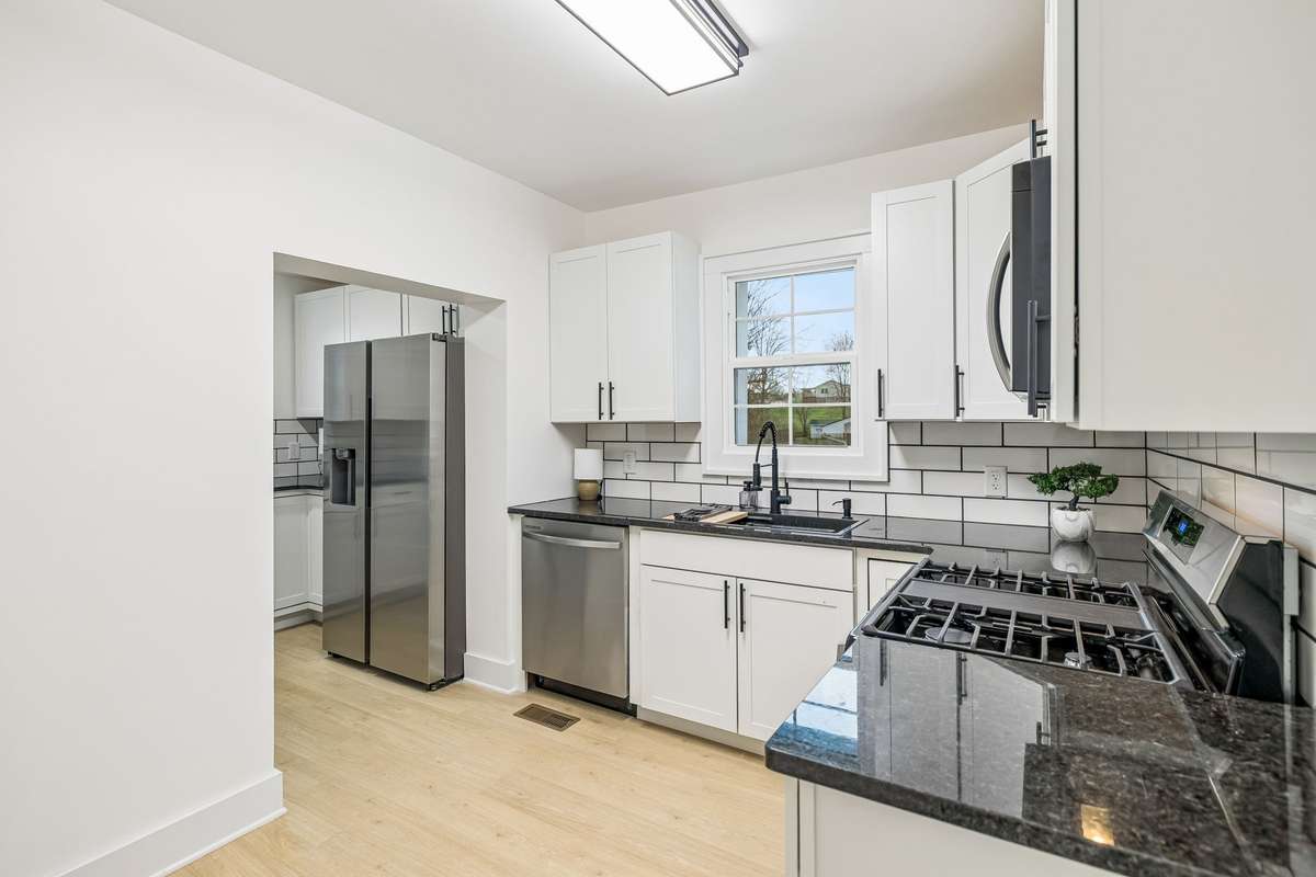 Brand new kitchen off of the dining room features new cabinetry, tile backsplash, solid surface counters, a GAS RANGE and BRAND NEW stainless steel appliances!