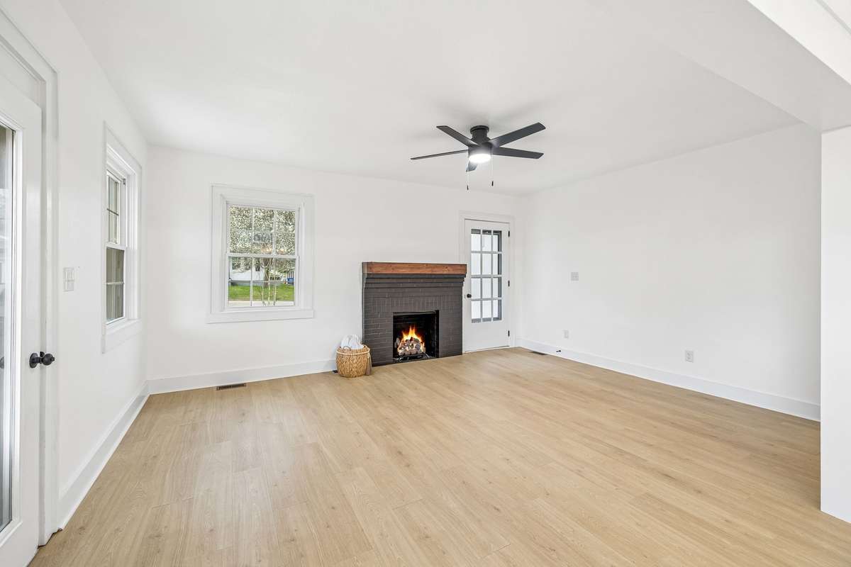 Living room with front and side entrance, gas log fireplace, new ceiling fan, new flooring, new paint