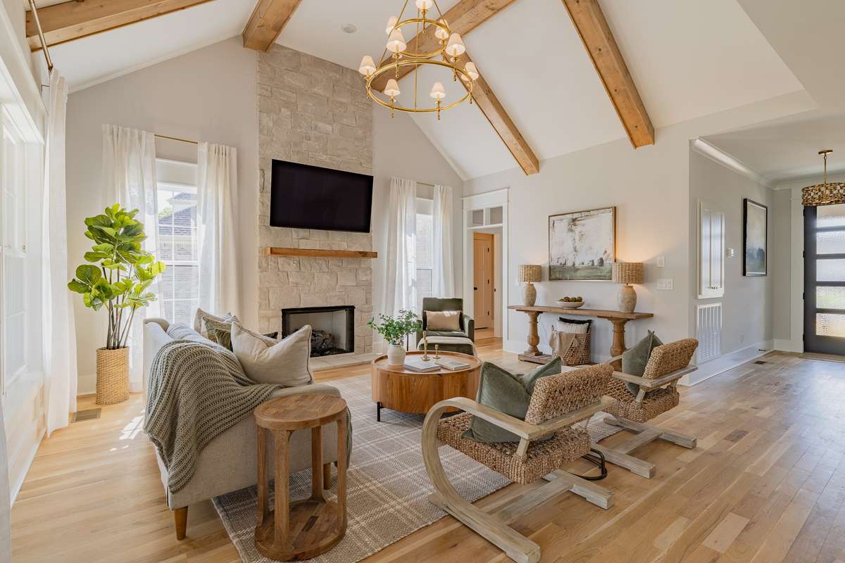 Living Room with Vaulted Ceilings, Exposed Beams, Visual Comfort Chandelier, and Stunning Austin Stone Fireplace