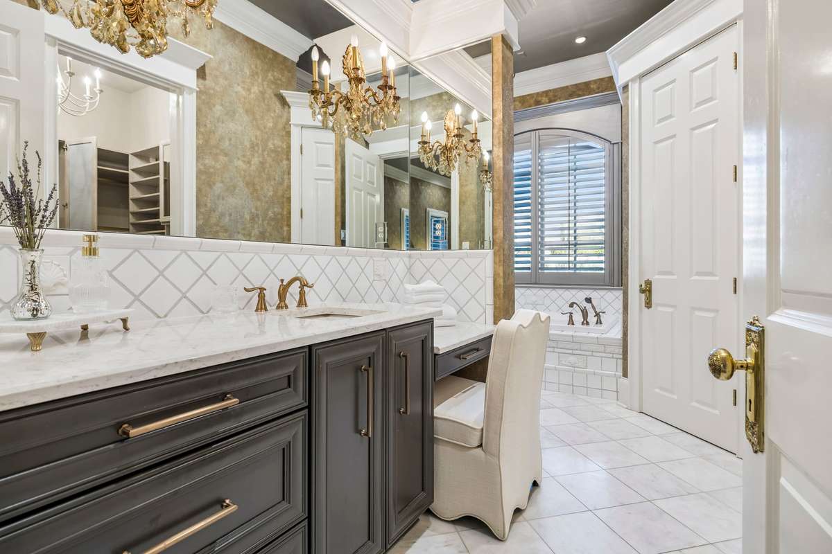 Spa-like bath with heated floors, marble counters, soaking tub, and dual walk-in-closets