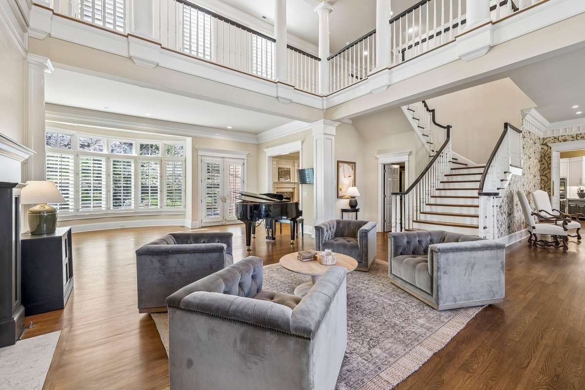 Elegant formal living room with gas fireplace, coffered ceilings, and architectural details. Soaring 22-ft ceilings and dramatic entry.