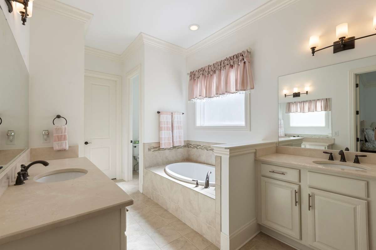Primary bath with double vanities, Jacuzzi tub, and tiled shower