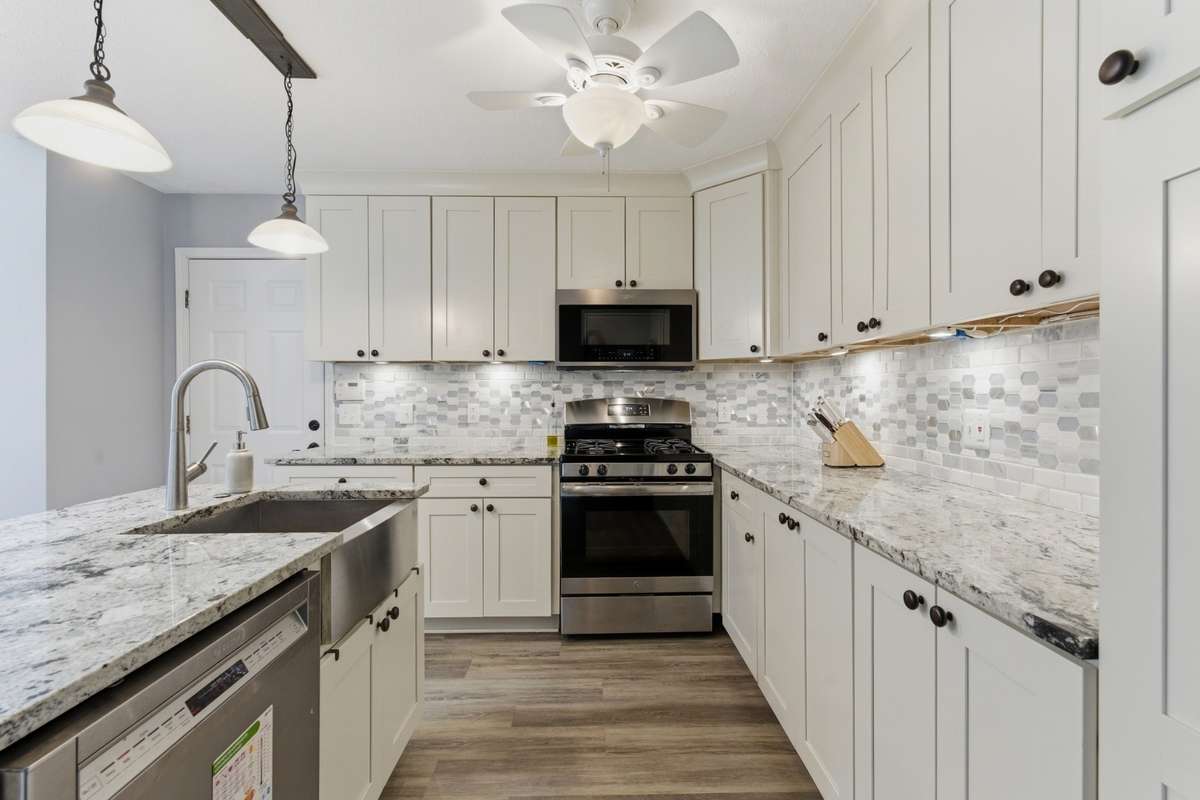 Kitchen with island featuring sink and dishwasher. Gas range ahead. Kitchen dining area to the left.