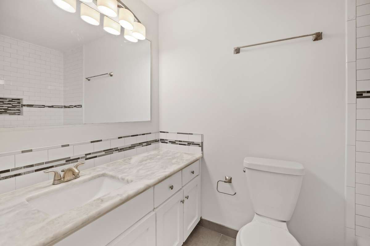 Full bath with granite counter and tile floor. Tub shower combo with tile surround.