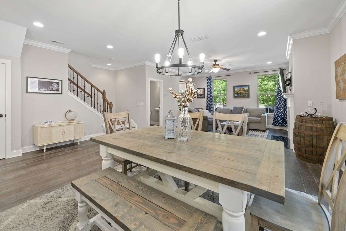 Alternate view of dining/living area.  This view shows wooden staircase with iron-style ballusters leading to upstairs.