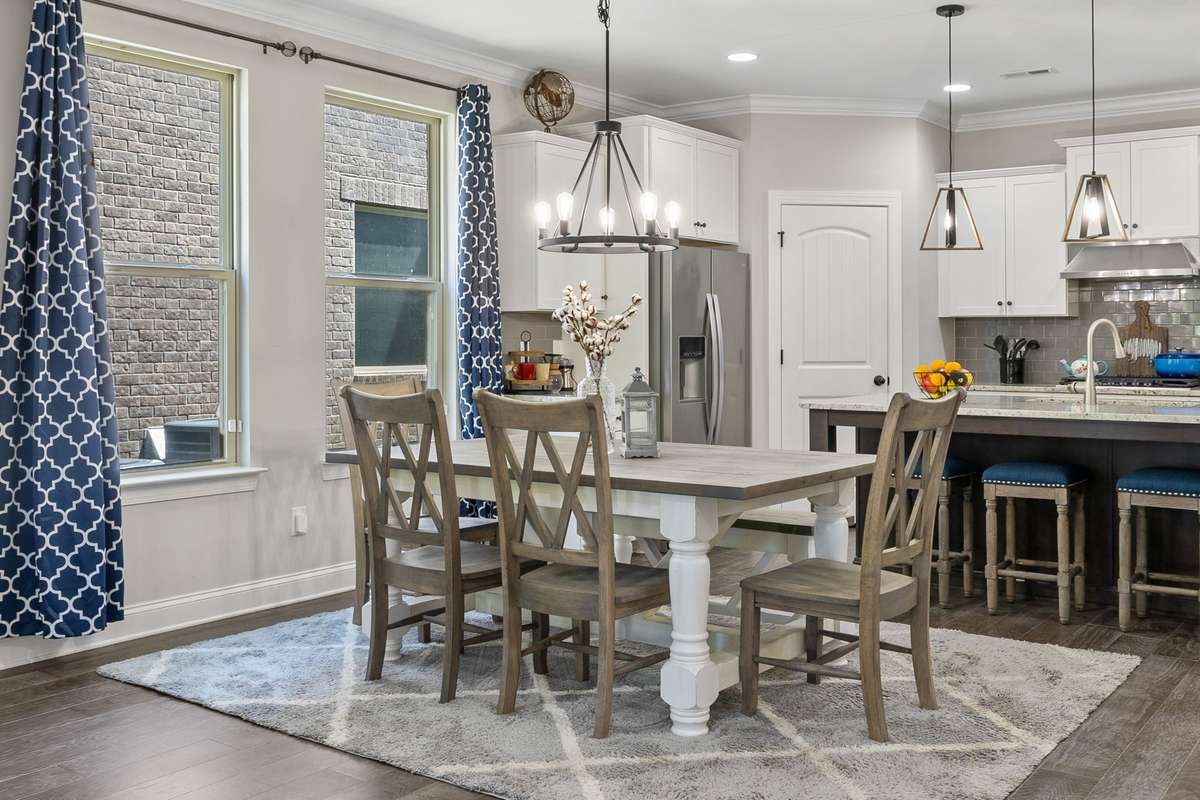 Attractive lighting over both the dining table (wagon wheel) and sconce lighting over kitchen island.  Additional recessed lights in Kitchen give this first story floorplan a bright and airy look.
Don't miss the pantry to the right of the Fridge!