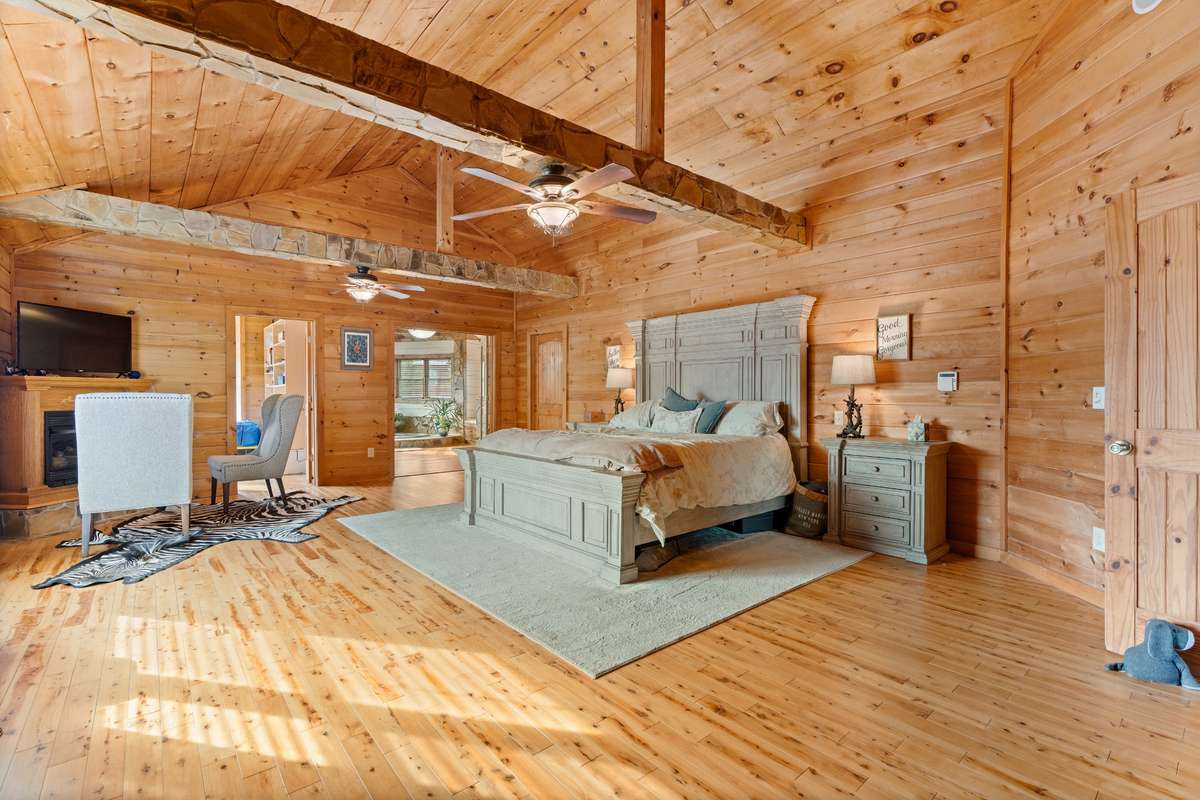 Sprawling primary bedroom on the main level with seating area and gas fireplace