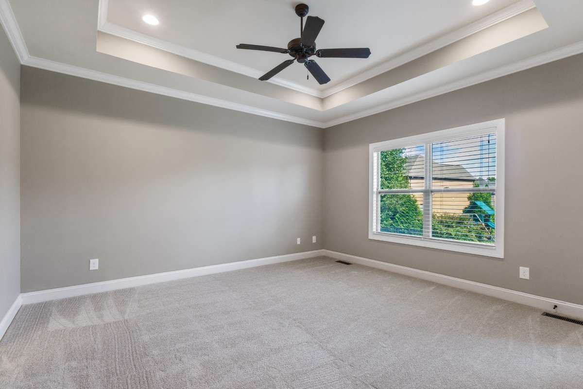 Owner’s suite retreat featuring a trey ceiling and ceiling fan, with direct access to the covered back porch for relaxing mornings or evenings