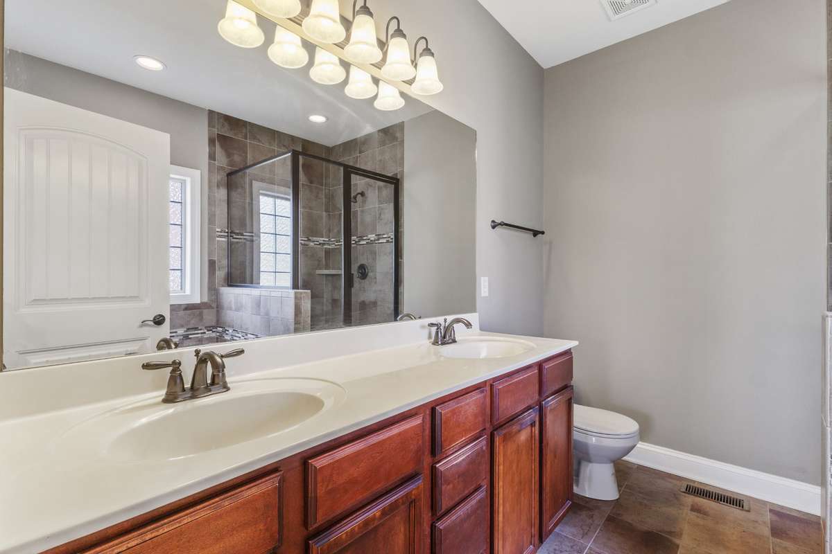 The spa-inspired owner’s bath showcases double vanities with expansive counter space and abundant cabinetry, creating a refined and practical space designed for both relaxation and everyday ease.