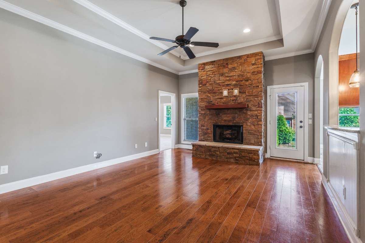 Light-filled great room featuring a floor-to-ceiling fireplace and full windows with direct exit to a covered patio ideal for cozy nights and sunny mornings alike.