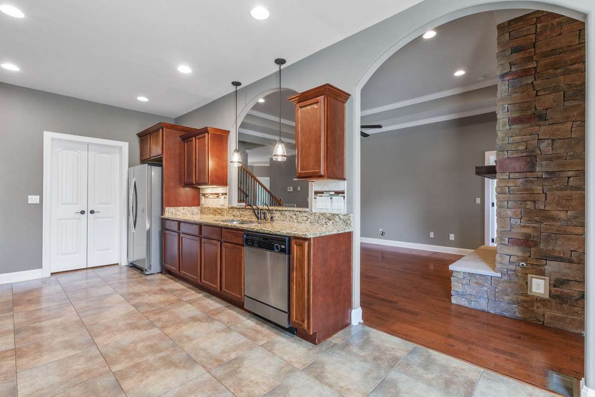 Chef-ready kitchen with tiled floors, recessed lighting, abundant cabinet space, granite countertops, and stainless steel appliances—ideal for family meals or entertaining guests.