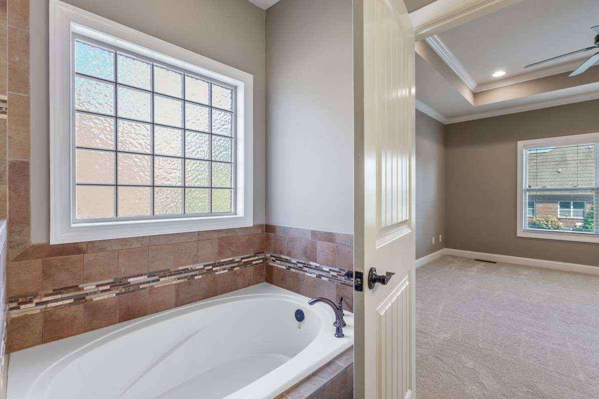 The owner’s suite bath is designed for relaxation, highlighted by a deep soaking tub that offers a serene, spa-inspired escape within the comfort of home