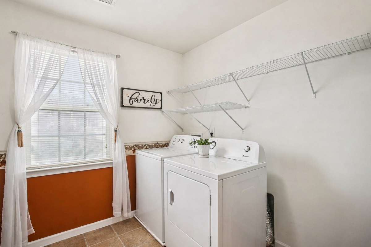Upstairs laundry room conveniently located near the primary suite, offering natural light, built-in shelving, and added everyday ease.