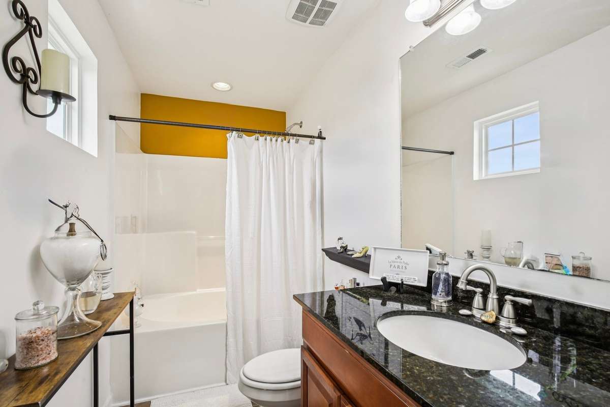Primary ensuite offering a shower/tub combo, generous vanity space, and an efficient layout.
