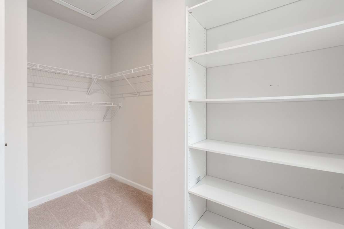 Spacious primary walk in closet with custom shelving