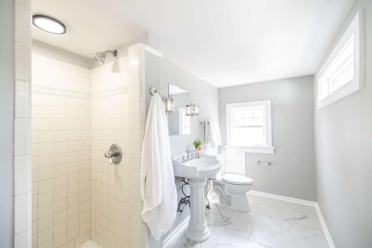 Beautifully updated upstairs bathroom with a tile shower and classic pedestal sink