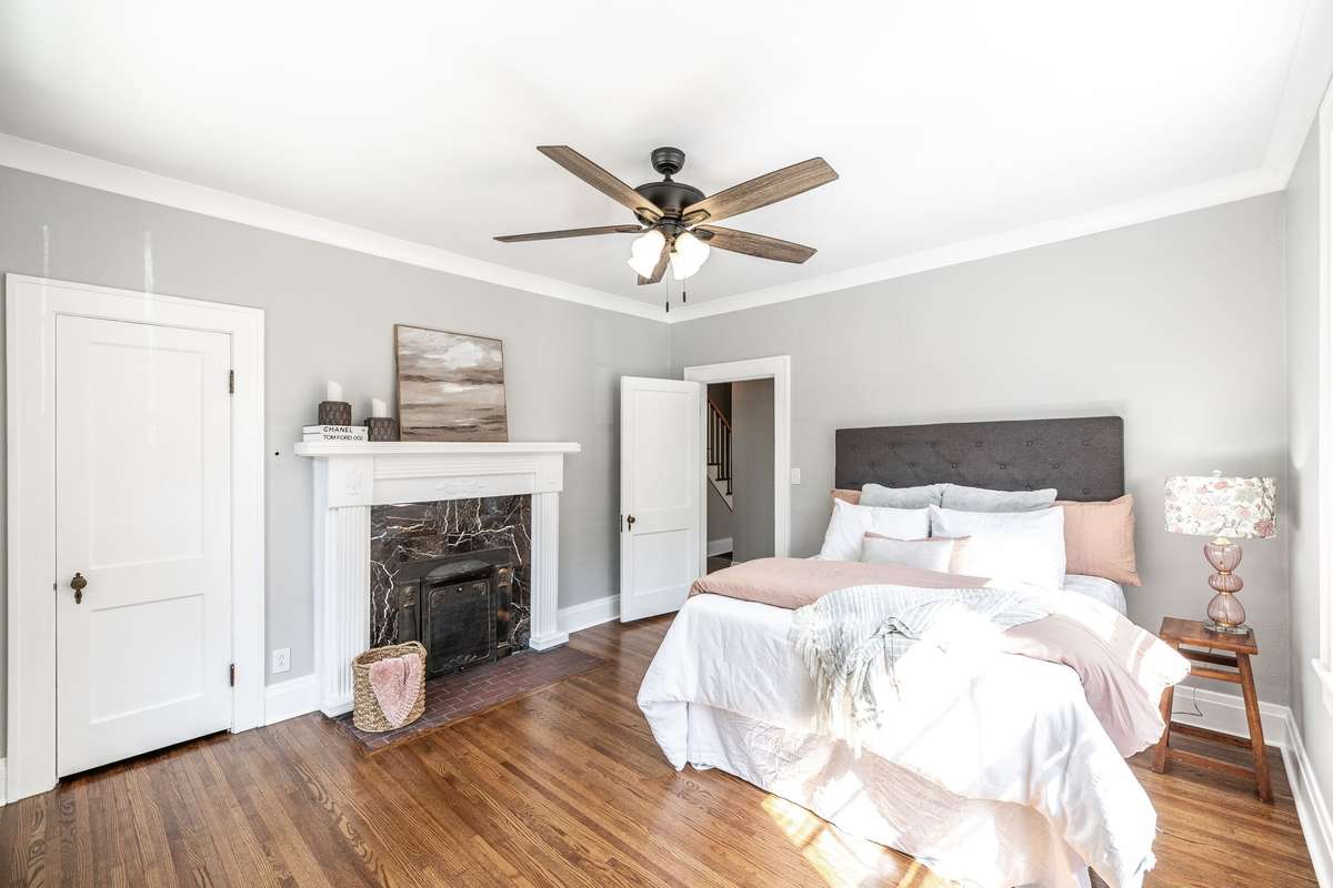Spacious main level bedroom with beautiful hardwood floors and an original fireplace adding warmth and character