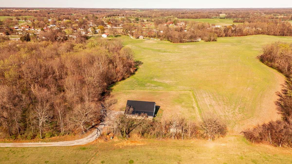 From above, you can truly appreciate the peaceful setting of this modern farmhouse, tucked behind a natural tree line and surrounded by open countryside on its spacious 1.35-acre lot.