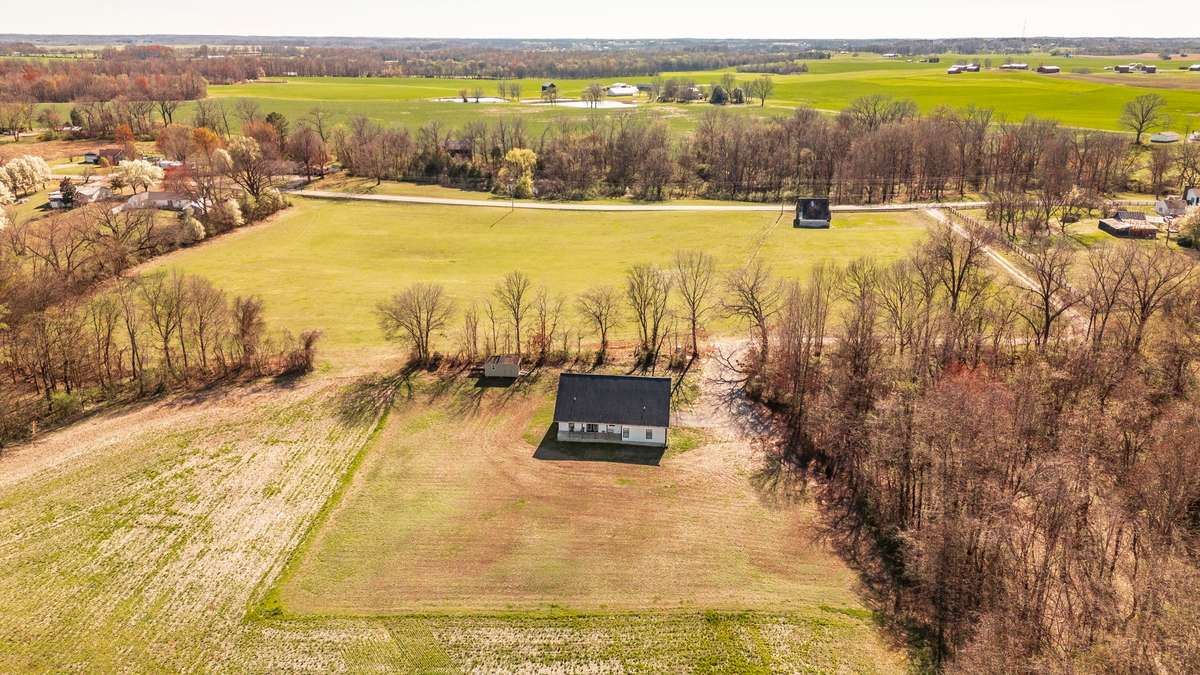 This aerial perspective highlights how the home sits comfortably back from the road, offering privacy and a welcoming approach framed by mature trees.