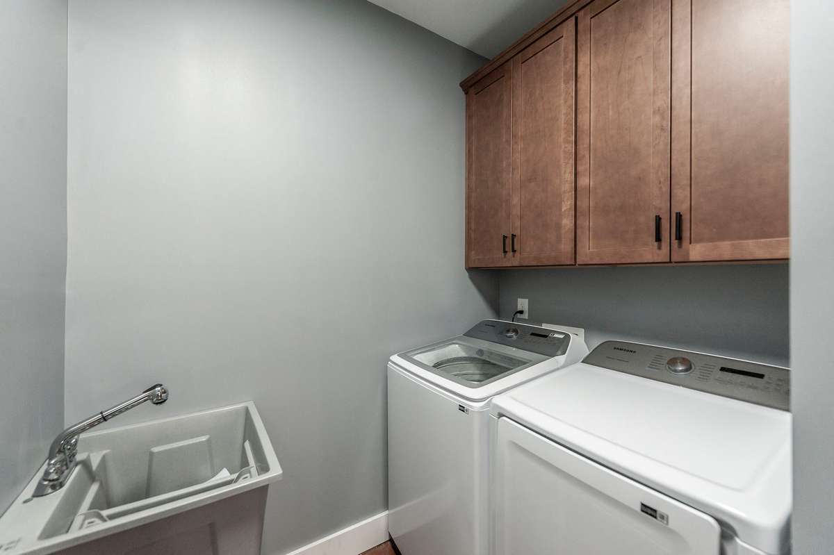 This spacious laundry room features plenty of cabinet storage, a convenient laundry sink, and room to organize essentials, making chores easier while keeping everything tidy and accessible.