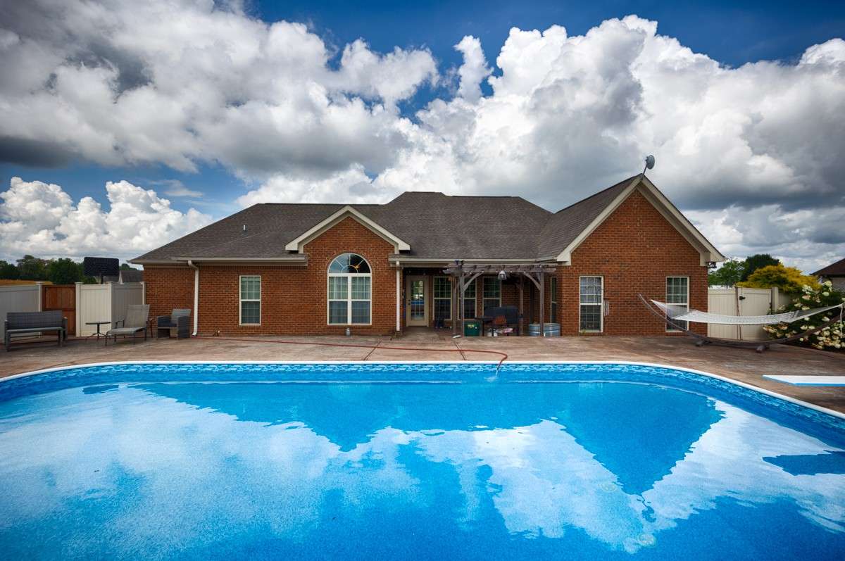 Back of house - Covered porch/patio, pool with new liner July 2025, diving board, privacy fenced yard