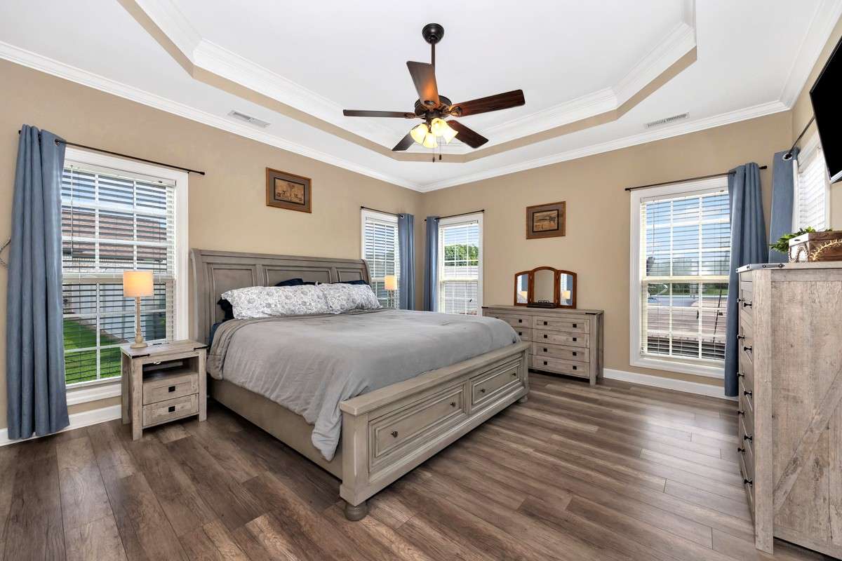 Primary Bedroom- LVP flooring, crown molding, trey ceiling, ceiling fan