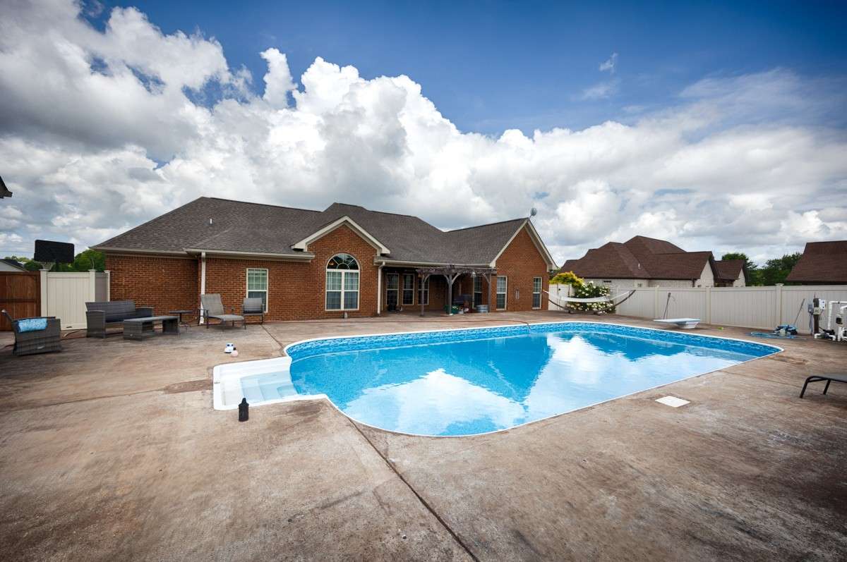 Back of house - Covered patio/porch, large poolside area for entertaining, new pool liner July 2025, privacy fence