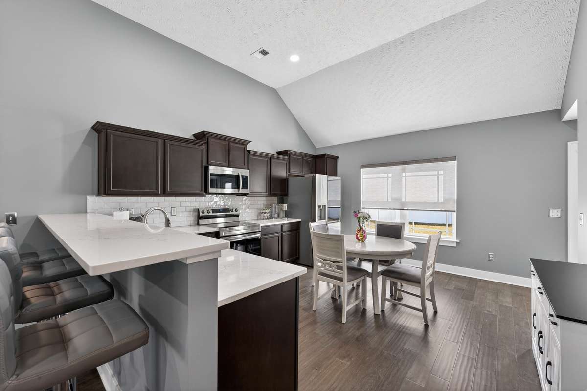 Subway tile backsplash and white quartz countertops keep the kitchen feeling clean and bright against the dark cabinetry.