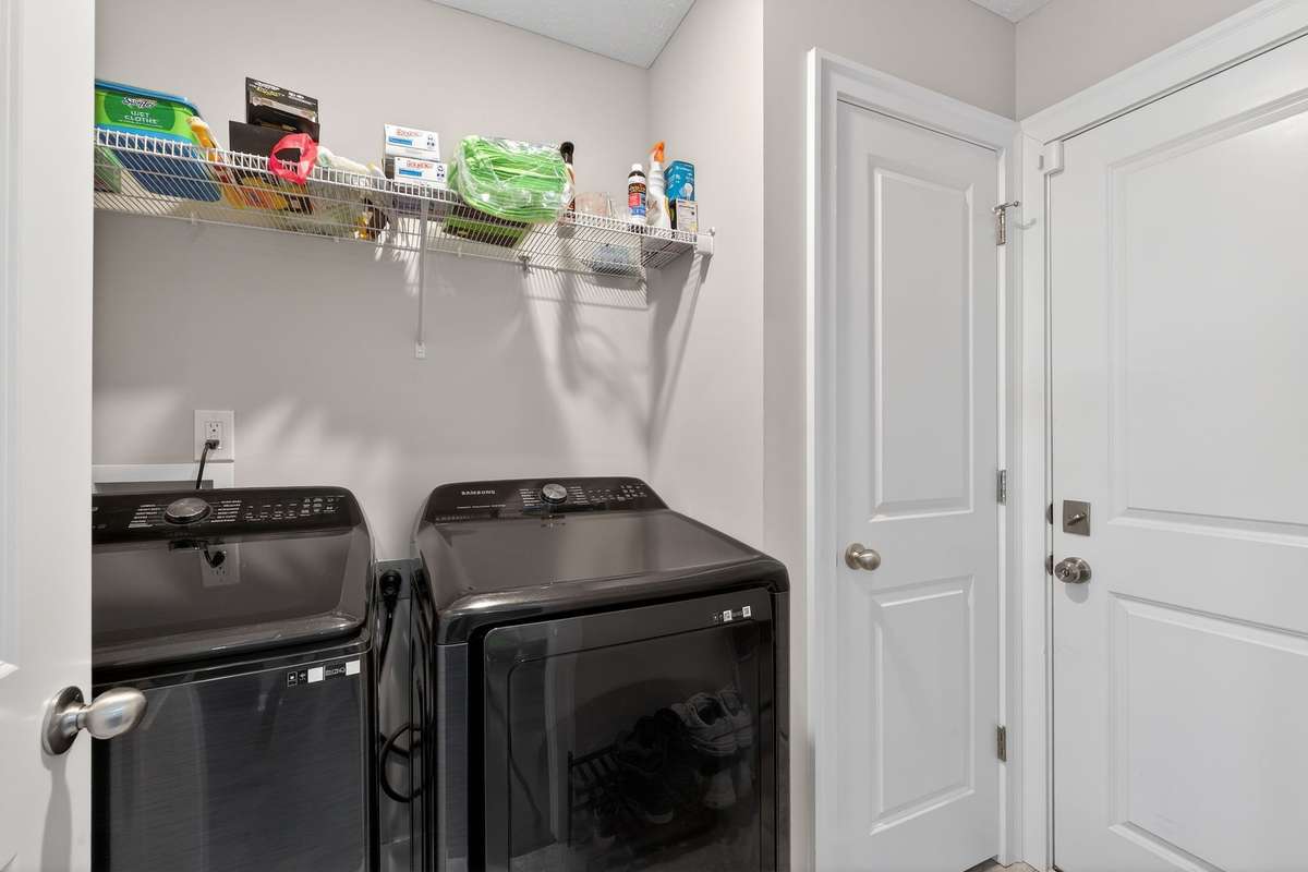 Convenient laundry room with wire shelving above the machines keeps detergent and supplies within easy reach.