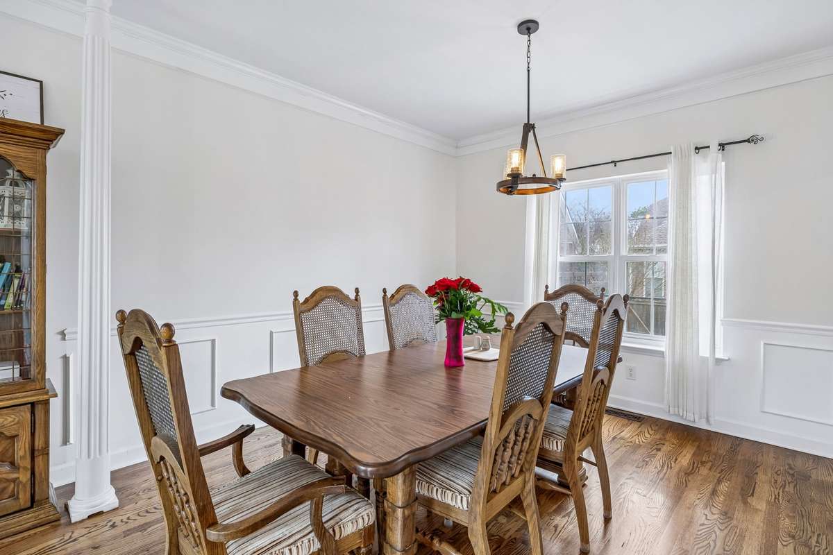 Formal dining room with rich hardwood floors, classic wainscoting, crown molding, and a stylish chandelier, all filled with natural light from the large windows! 1407 Ottawa Place, Murfreesboro, TN 37129