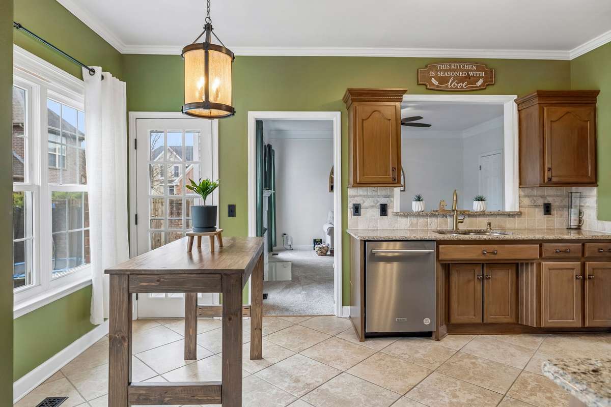 Bright kitchen with warm wood cabinetry, stylish lighting & tile backsplash, and an easy connection to the dining room for seamless meals and gatherings! 1407 Ottawa Place, Murfreesboro, TN 37129