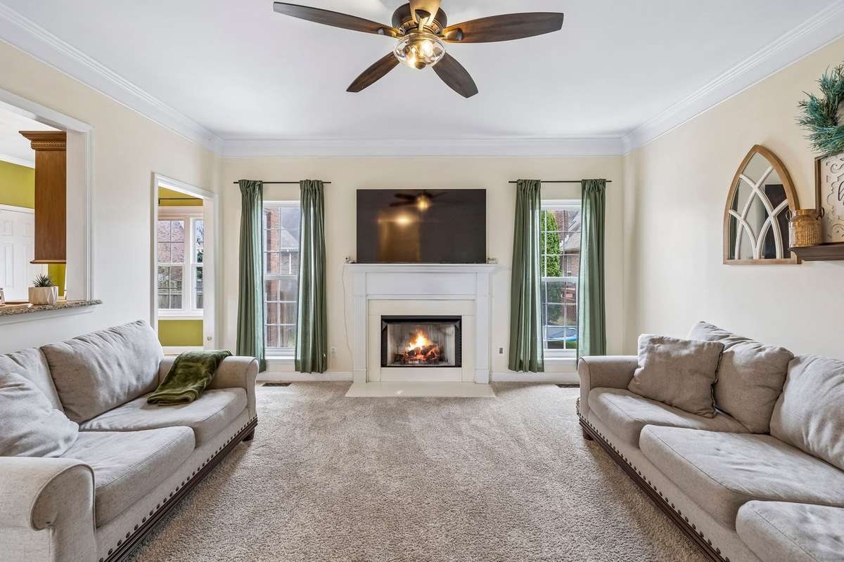 Comfortable living room centered around a cozy fireplace with classic mantel, crown molding, and large windows that fill the space with natural light! 1407 Ottawa Place, Murfreesboro, TN 37129