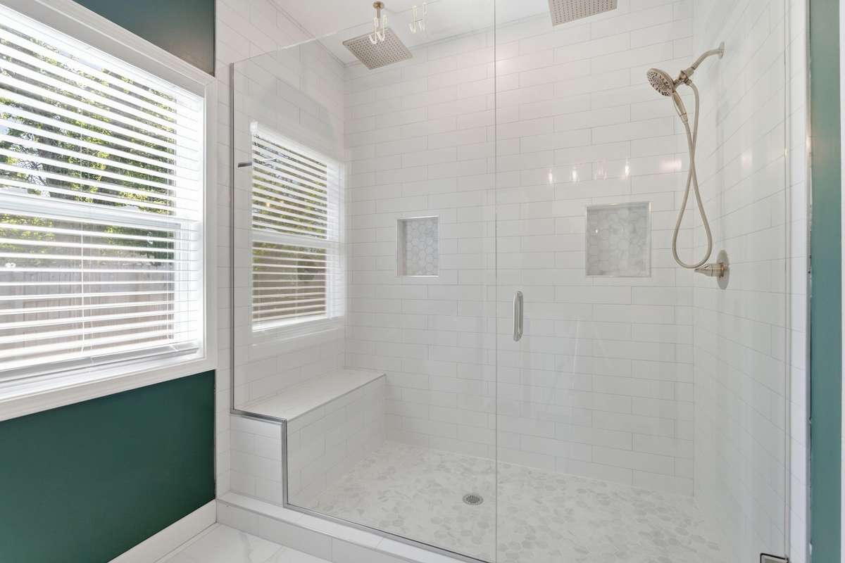 Extra large shower with double rain, head, double niche handheld and bench seat.