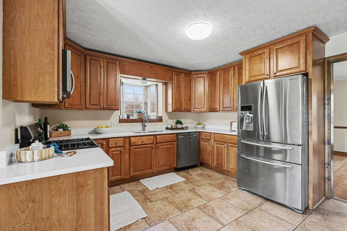 A Beautiful Kitchen Featuring Warm Wood Cabinetry with Plenty Of Counter Space And Natural Light That Make This Kitchen Shine