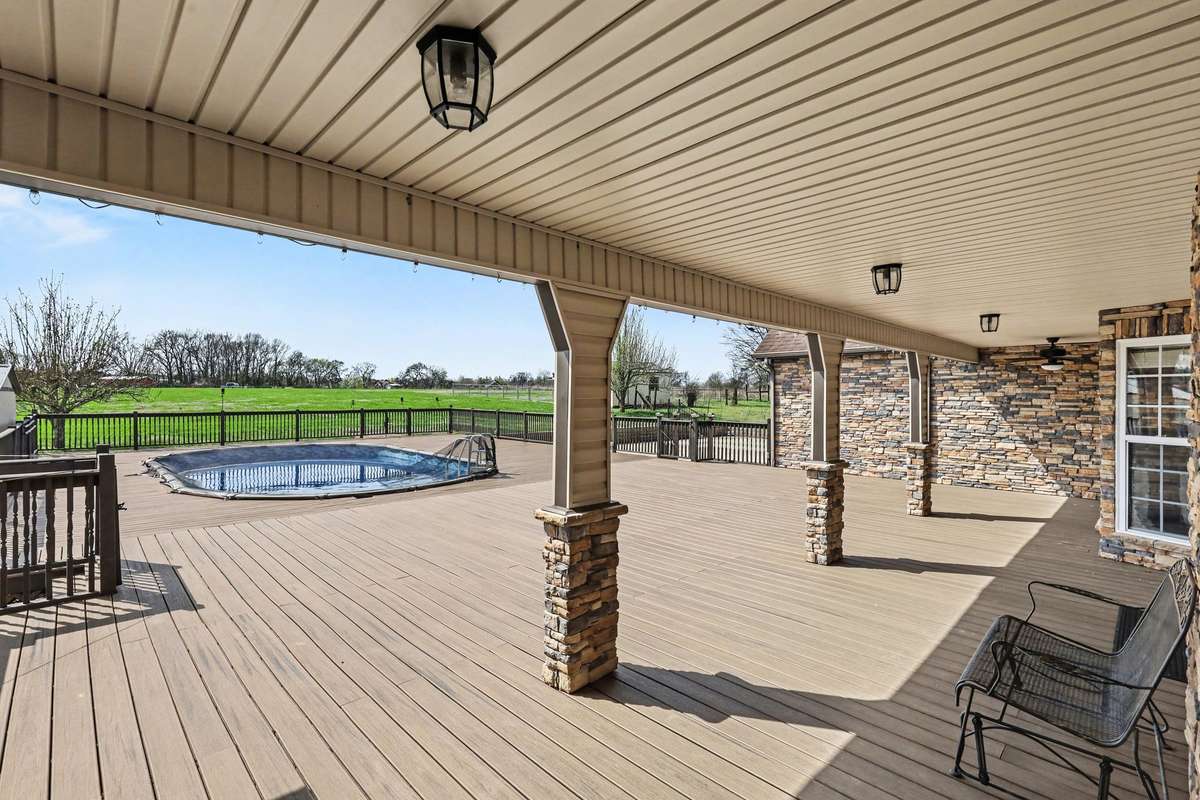 Resort-Style Outdoor Living With A Covered Deck And Pool Surrounded By Peaceful Country Views
