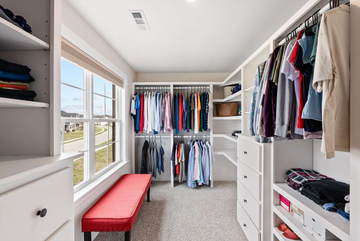 Spacious primary closet with custom built-ins, abundant storage, and a window for natural light—combining functionality with a bright, boutique-style feel.