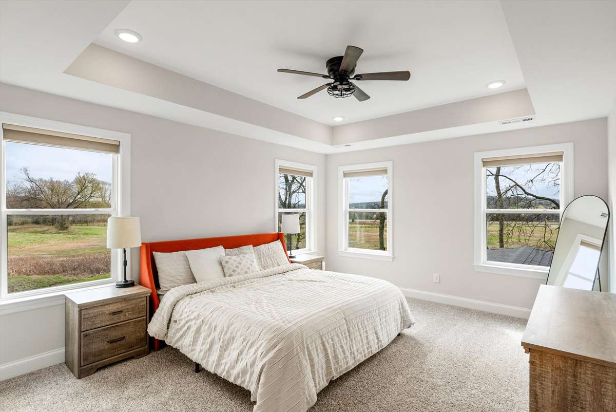 Light-filled primary suite with tray ceiling, expansive windows, and peaceful views—creating a calm and spacious retreat.