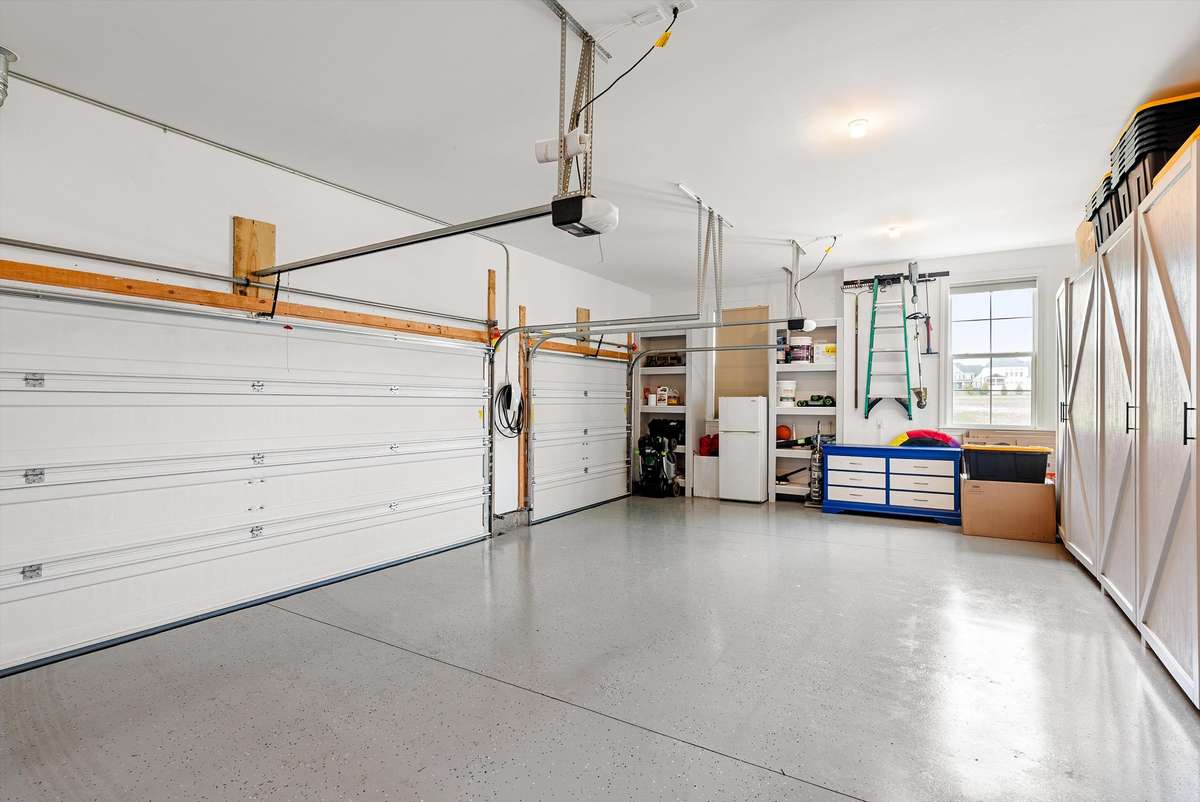 Spacious garage with epoxy flooring and extensive storage solutions, offering plenty of room for vehicles, equipment, and everyday organization.