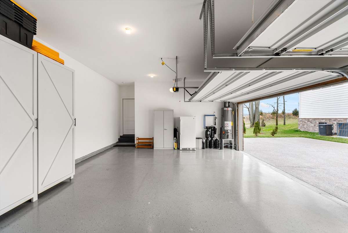 Clean, well-organized garage featuring durable epoxy flooring and built-in cabinetry—offering both low-maintenance functionality and ample storage.
