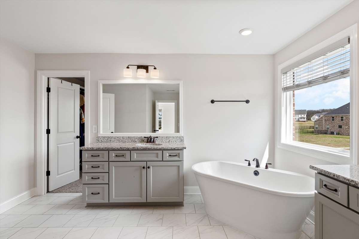 Bright and elegant bathroom with a freestanding soaking tub, spacious vanity, and large window bringing in natural light