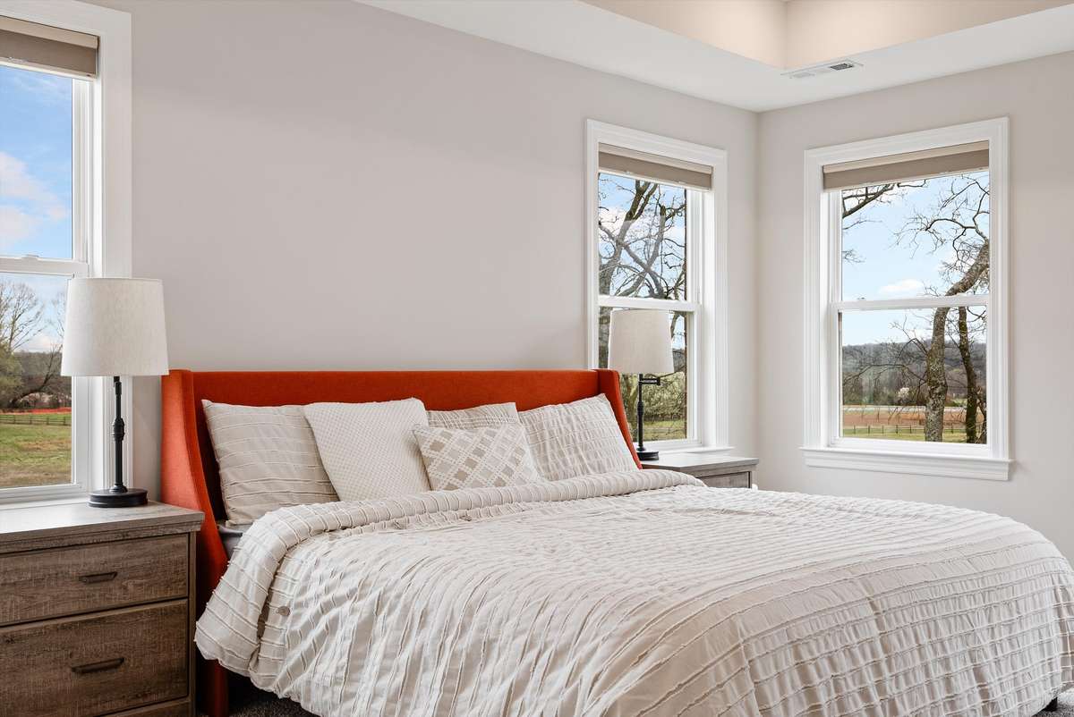 Additional windows were thoughtfully added during construction to maximize natural light and capture beautiful surrounding views, creating a bright and inviting bedroom retreat.