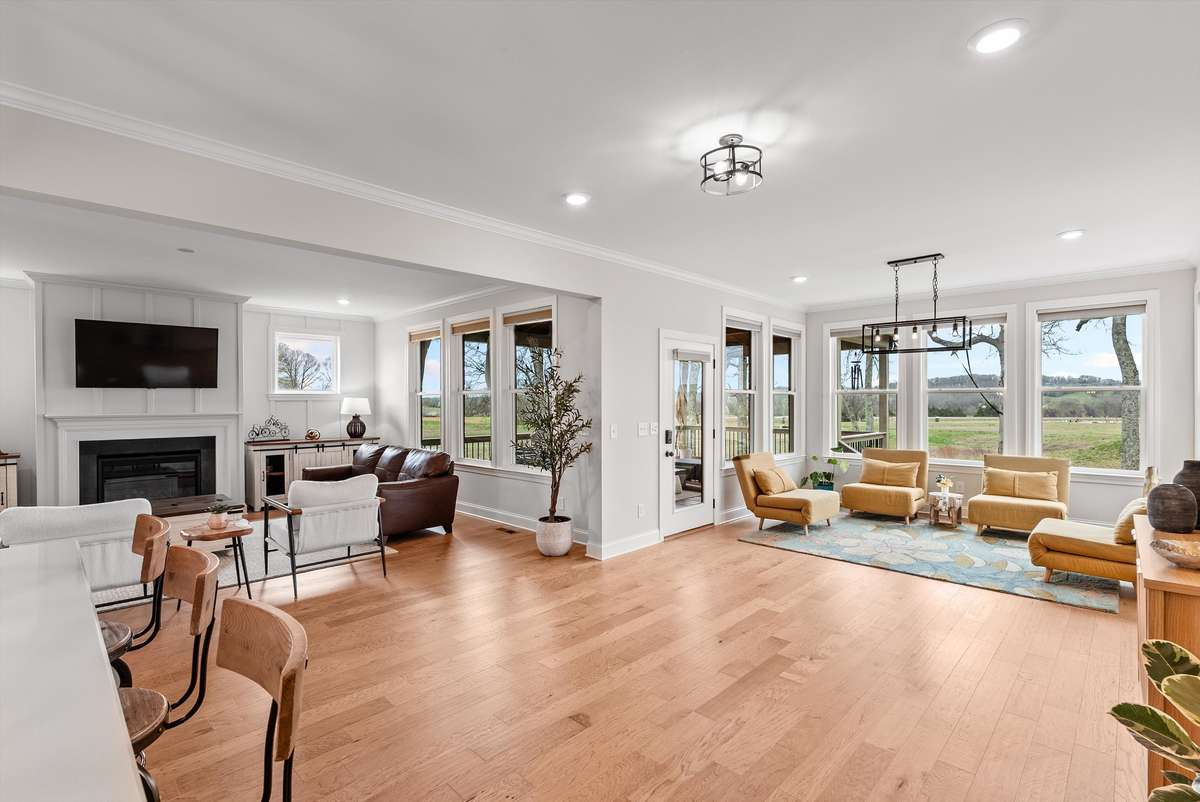 Light-filled living and dining areas with expansive windows, warm hardwoods, and multiple gathering spaces that flow effortlessly throughout the home.