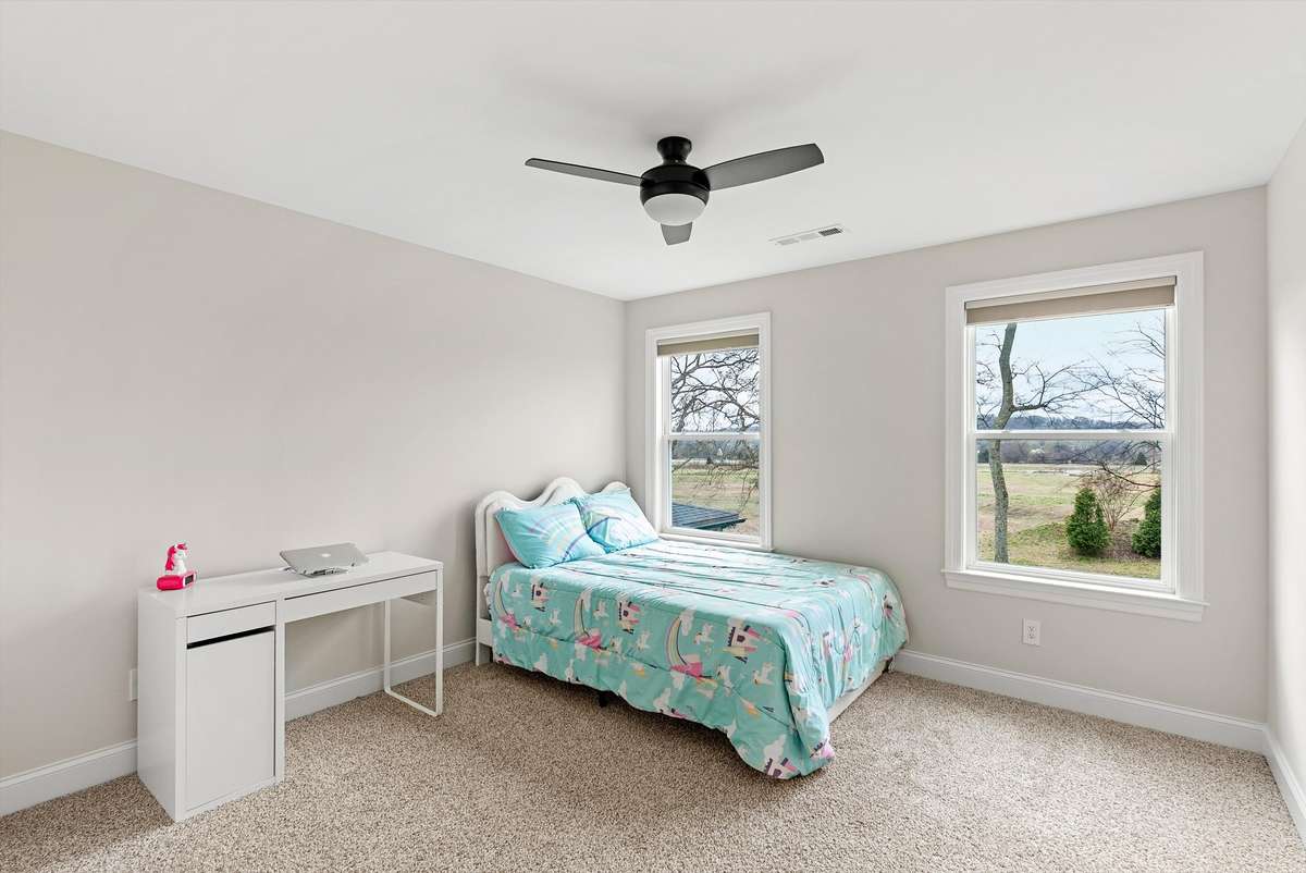 Light-filled secondary bedroom with two windows, soft neutral tones, and a flexible layout—ideal for guests, family, or a home office.