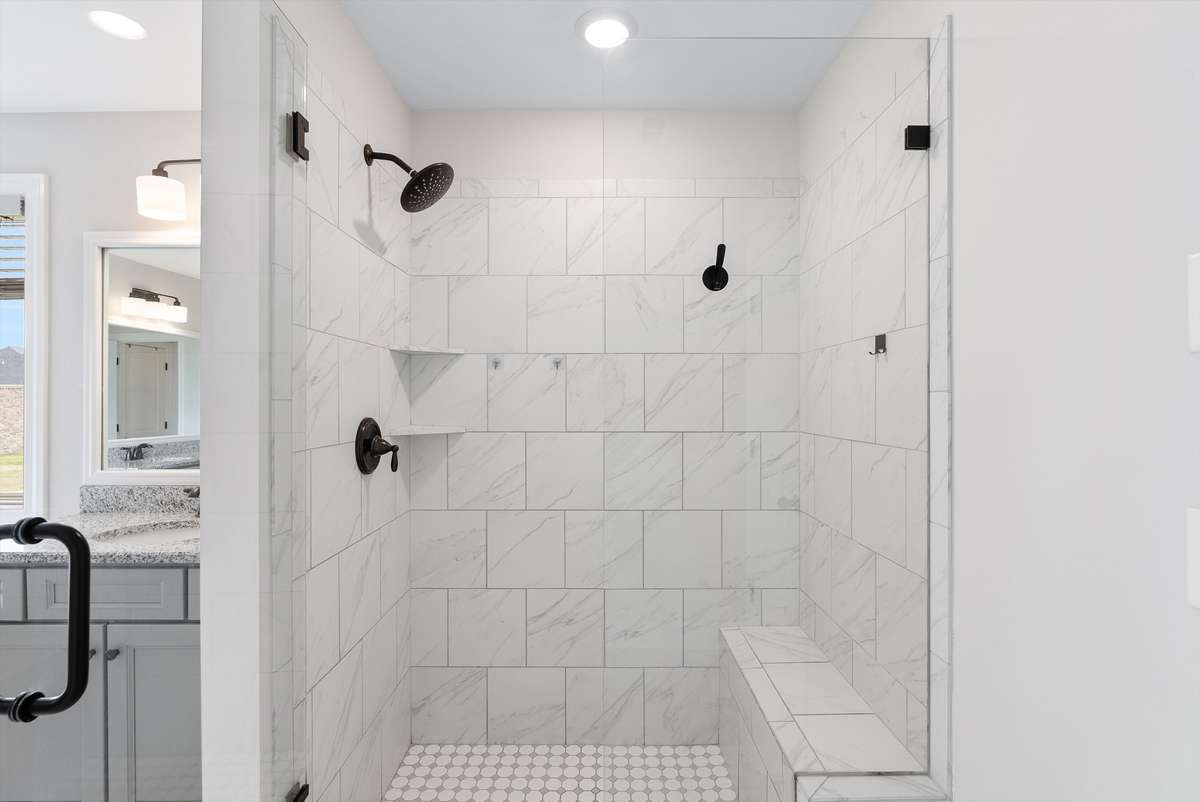 Spacious walk-in shower with classic tile, built-in bench, and dual showerheads