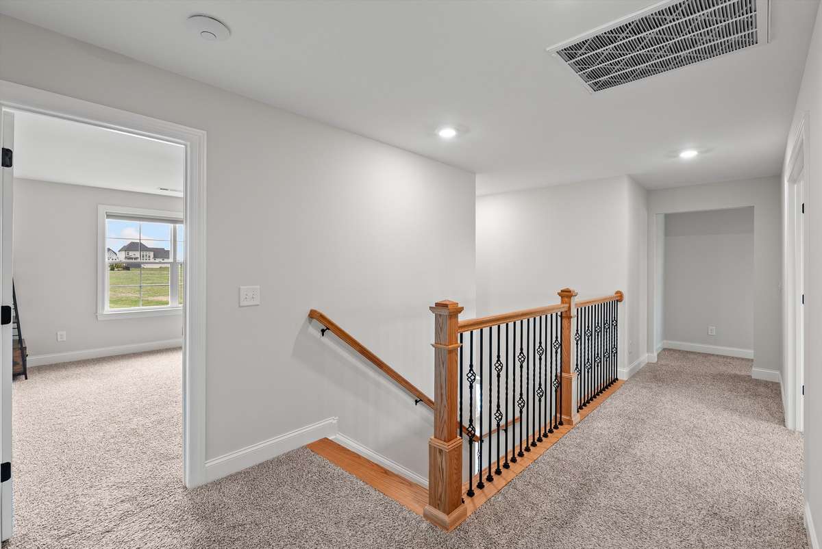 Bright and open upper-level hallway with quality wood and iron railing, offering a flexible space that connects comfortably to surrounding bedrooms.