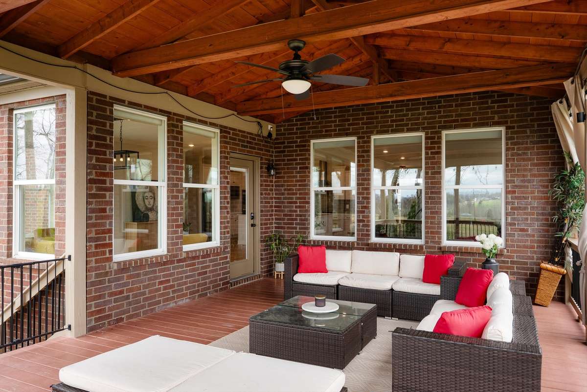 Inviting covered outdoor living area with rich wood ceiling and brick backdrop—creating a private, all-season space for relaxing or entertaining.