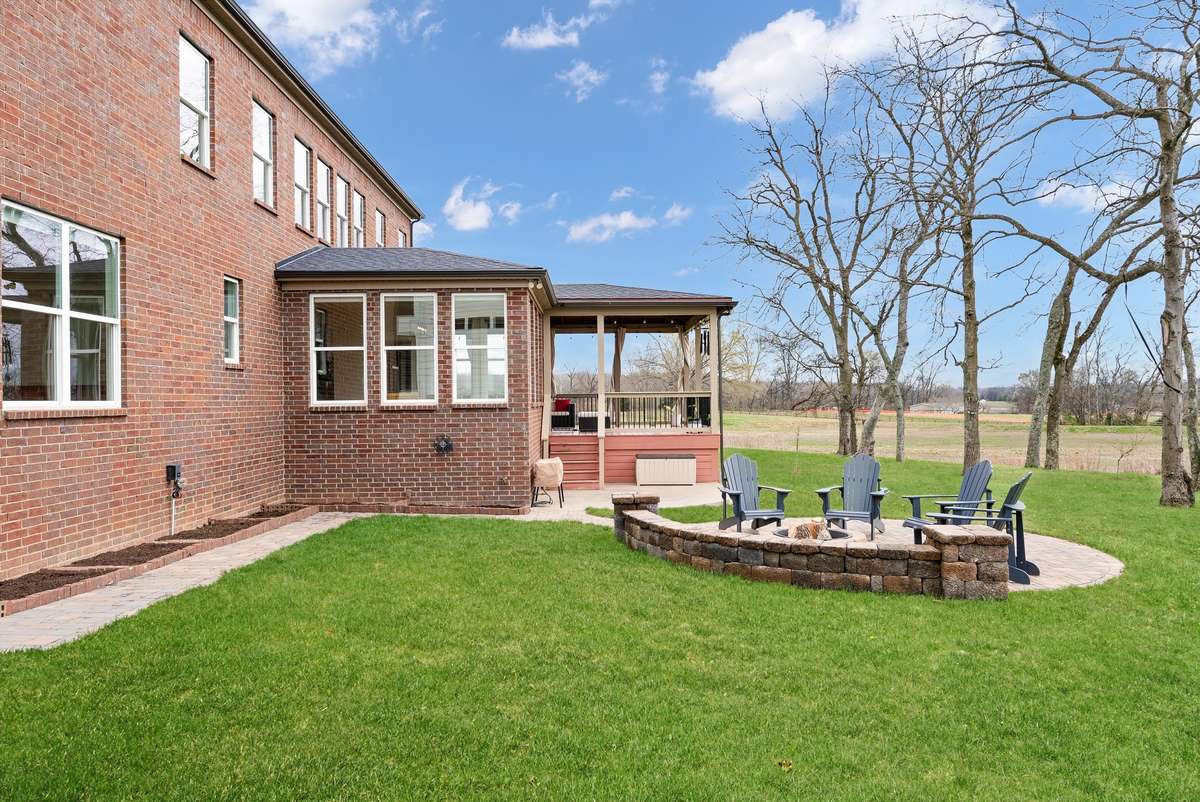 Private backyard retreat featuring a spacious lawn, custom fire pit area, and covered outdoor living space—all set against peaceful, scenic views.