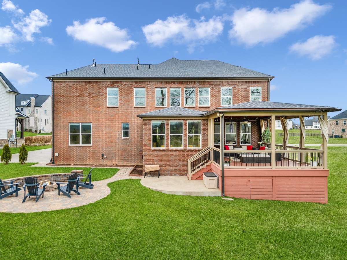 Beautifully designed outdoor living with a covered deck, fire pit gathering area, and expansive lawn—perfectly positioned to enjoy the surrounding countryside views.