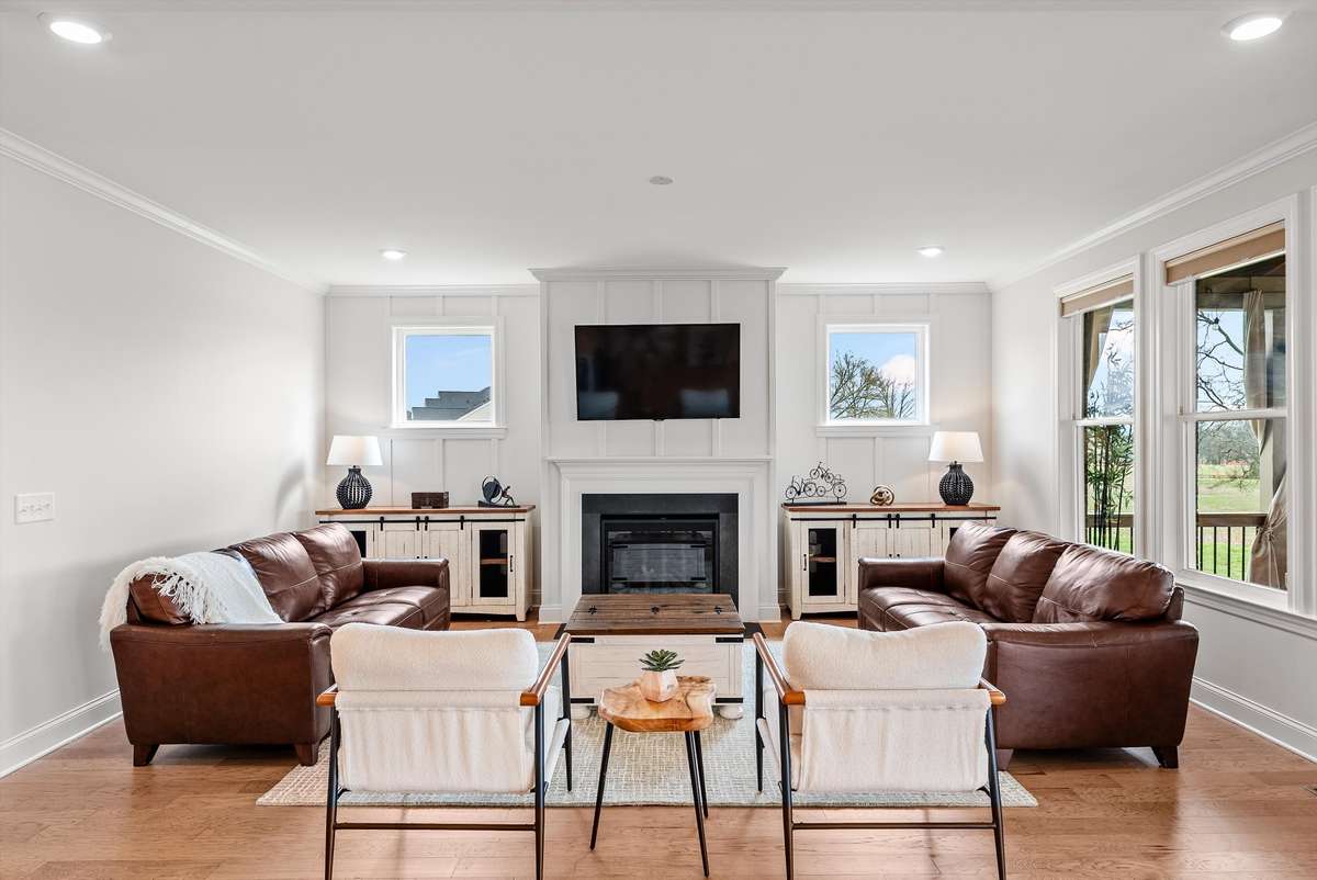 A perfectly balanced living room centered around a cozy fireplace, with warm wood tones, abundant natural light, and an inviting layout designed for both comfort and conversation.